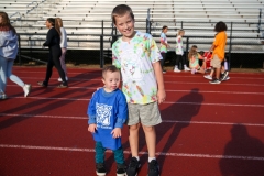 Two people standing on a track, one adult and one child, both wearing t-shirts with designs on them.