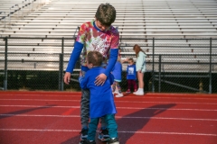 Two children walking together on a track in a stadium.