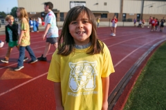 Girl in yellow shirt holding a cat on her shoulder.