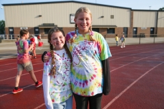 Two young girls posing in front of a track at a walkathon event.