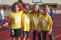 Four children posing in front of a track for a walkathon event.