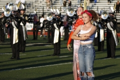 Woman in front of marching band, smiling and posing for picture.