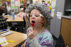 Girl in costume licking a tootsie pop.