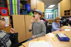 Two children enjoying lollipops at a table in a classroom.