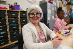 Little girl in glasses sitting at a table with toy popsicles.