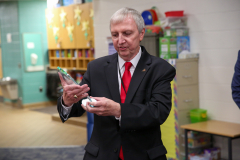 Man in suit holding a small trophy.