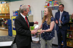 Man in suit congratulating woman on her work, both smiling at each other.