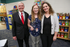 Three people posing in a library setting, possibly for an event or ceremony.