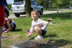 Little girl kneeling at a grave in a cemetery.