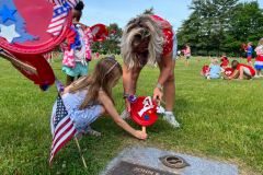 Woman and child placing flowers on a grave marker.