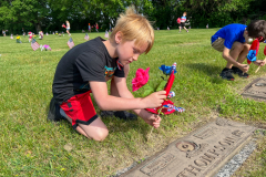 Two boys placing flowers on a grave.