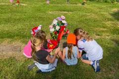 Three children standing by a grave decorated for Memorial Day.