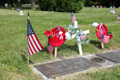 Memorial grave decorated with patriotic flags and flowers.