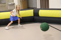 Little girl playing pool in a room with black and yellow furniture.