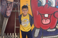 Little boy standing in front of a large apple sculpture.