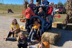 Group of people posing in front of a truck at an apple orchard.