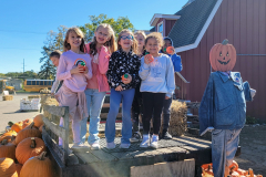 Children posing in front of a pumpkin patch at an apple orchard.