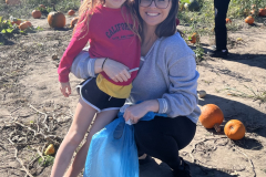 Woman and child standing near pumpkins in a field.