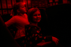 Two children sitting in a dark movie theater.