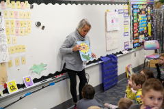 Woman standing in front of whiteboard filled with educational materials, holding a book.
