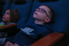 Two children watching a movie in a theater.