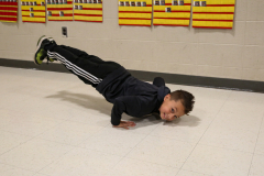 Young boy performing handstand in gym.