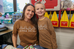 Woman and child standing in front of a classroom desk.