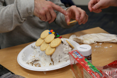 Gingerbread house decorated with cookies, candy, and icing, on a table during a gingerbread week event.