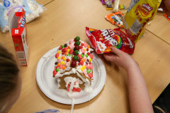 A gingerbread house decorated for Christmas, placed on a dining table.