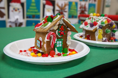 Two gingerbread houses on a table, one decorated like a Christmas house and the other like a Halloween house, both adorned