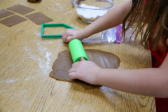 Girl making gingerbread cookies at a table.
