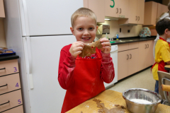 Young boy holding a gingerbread cookie in a kitchen.
