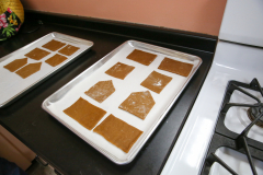Gingerbread cookies cooling on a baking sheet in front of an oven.