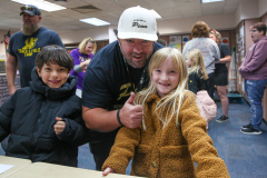 Man in a white hat posing for picture with two children and another man.