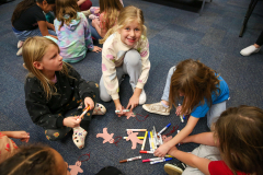 Children sitting on floor playing with gingerbread pieces.
