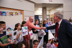 Man shaking hands with children at a school event.