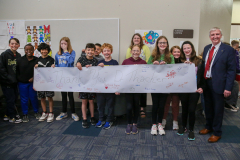 Group of people posing with a banner that reads "250522 Thacker Parade".