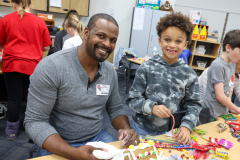 Two people, a man and a child, sitting at a table covered in candy.