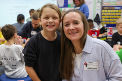 Woman and child standing near table in classroom setting.
