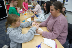 Woman and child making gingerbread houses at a table.