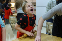 Young girl in kitchen, holding dough, making gingerbread.