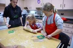 Two young girls in a kitchen, making gingerbread cookies.