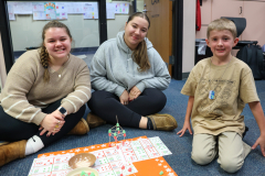 Three people sitting on the floor playing a board game.