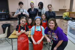 A group of children in aprons posing for a picture in a kitchen.