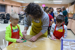Woman and two children in a kitchen, making gingerbread cookies.
