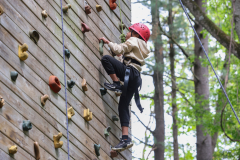 Child climbing a rock wall at camp.