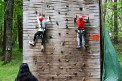 Two children climbing a rock wall at camp.