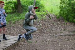 Man holding a stuffed animal over his head while jumping on a wooden platform.