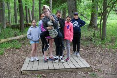 Children playing on a rope bridge in a forest.