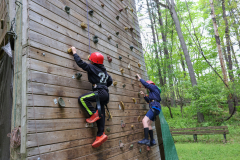 Two people climbing a rock wall at camp eberhart.